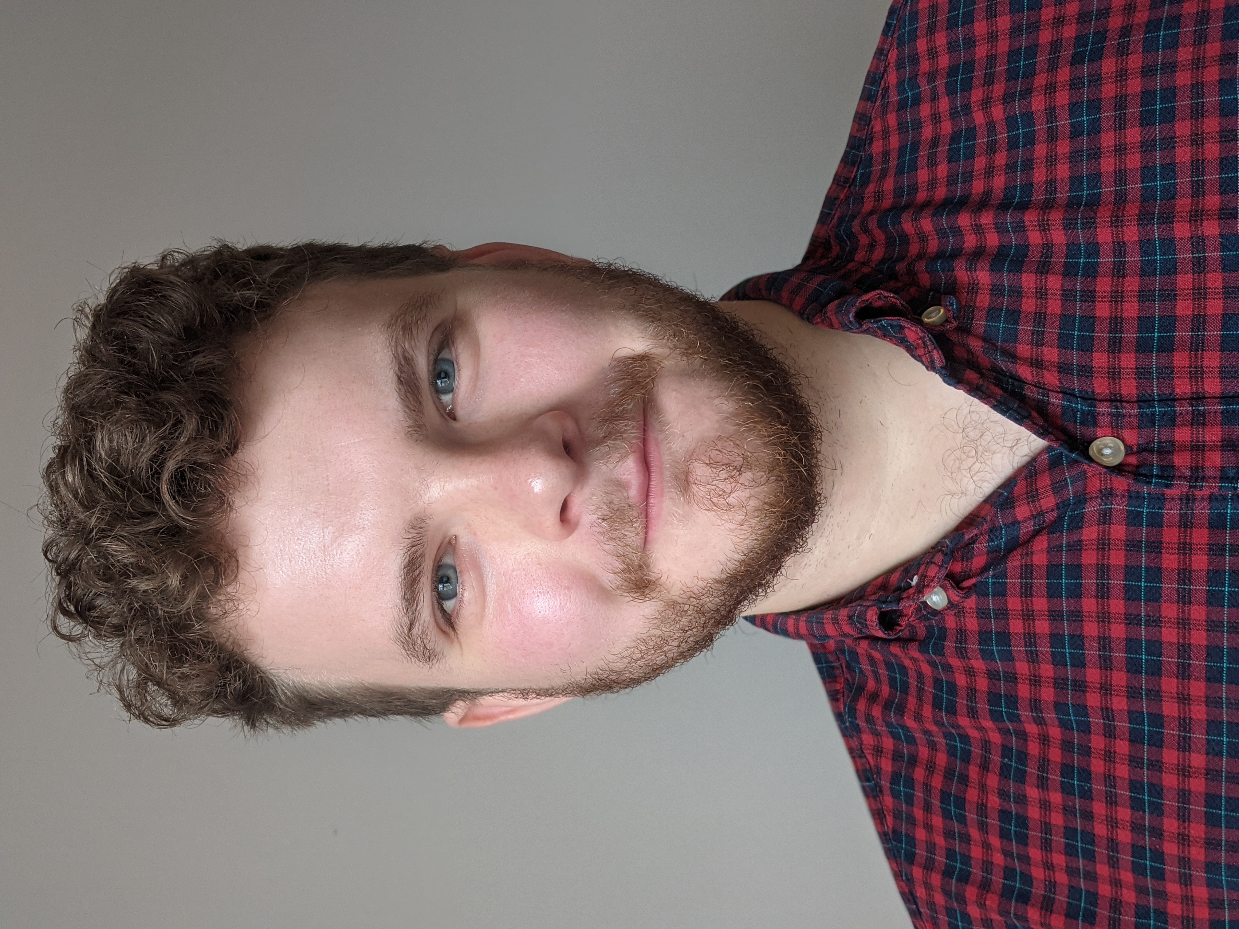 a headshot of Chris Murphy wearing a chequed shirt smiling at the camera